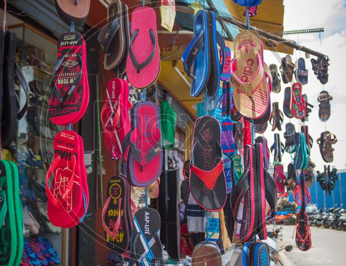 A Street Footwear shop displaying the Slippers in a innovative way in rural Mysuru cityscape of Karnataka state in India.