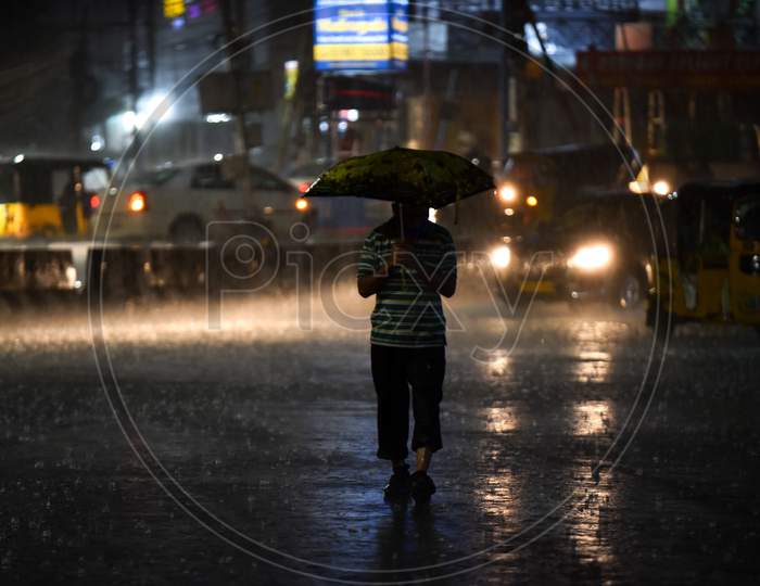 a man walks on the road at a traffic signal as it rains heavily in Hyderabad , September 16, 2020.