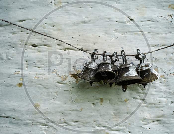 Old Vintage Bells Hanging On A White Wall Temple In India