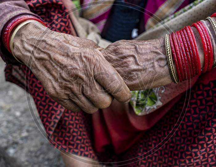 Hands Of An Elderly Indian Woman Resting On Her Red Saree.