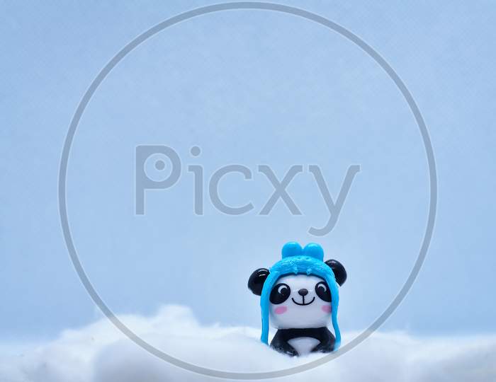 Little Panda Porcelain Figurine In Winter Snow Isolated On Black Background