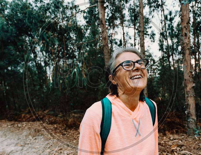 Old Woman Laughing In The Middle Of The Forest In Spain Wearing Sport Clothes With Copy Space