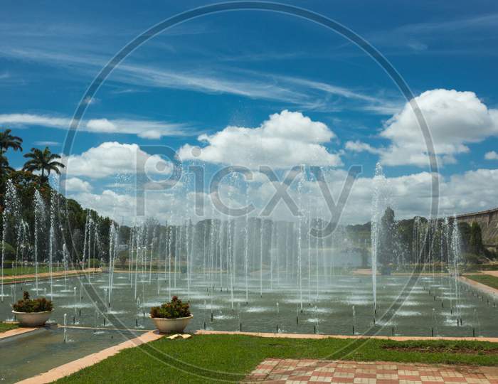 A Bewitching view of a Musical Water Fountain against the deep blue sky and silver clouds at Brindavan garden in Krishnaraja Sagara near Mysuru/Karnataka/India.