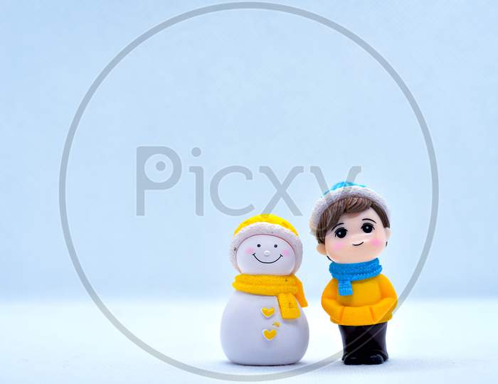 Tourism And Travel Concept: Miniature Little Boy And Snowman Standing In Isolated Background