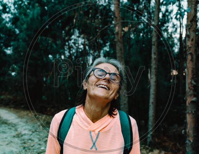 Old Woman Laughing In The Middle Of The Forest In Spain Wearing Sport Clothes