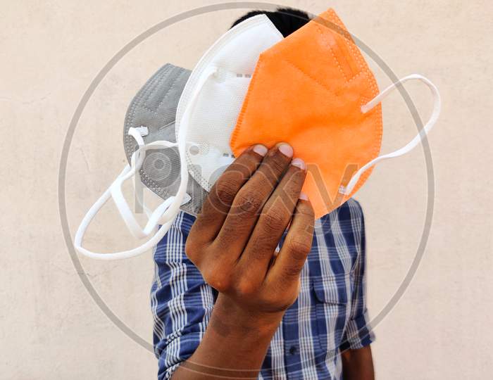 South Indian Man Showing Three Kn-95 Face Masks In White,Grey And Orange Color. Isolated On White Background.