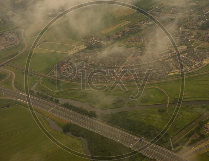 Farms, Highway In Holland, Netherlands With Canal Viewed From Plane In Sky With Clouds