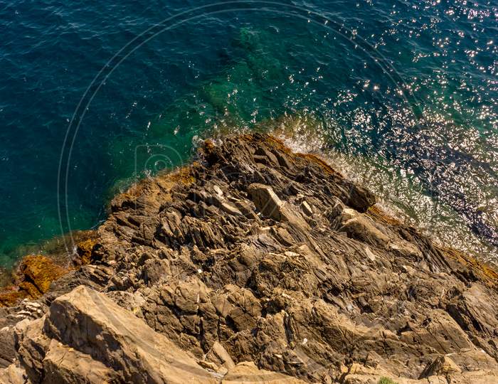Italy, Cinque Terre, Manarola, A Rocky Shore Next To A Body Of Water