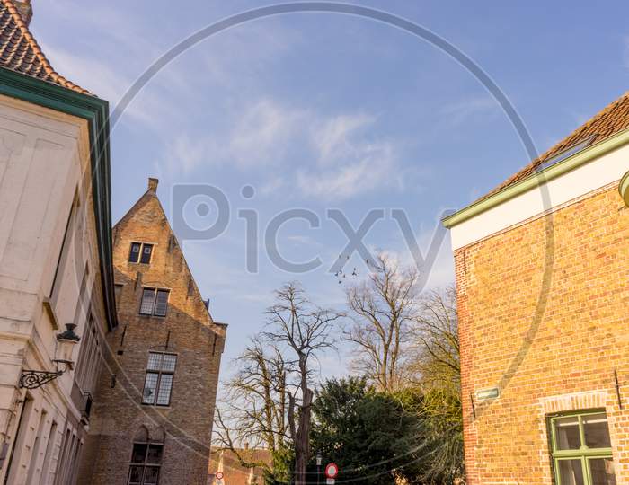 Belgium, Bruges, A Clock Tower In Front Of A Brick Building