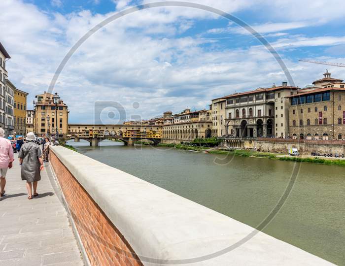 Florence, Italy - 25 June 2018: Tourists Walking Near The Ponte Vecchio Over The Arno River In Florence, Italy