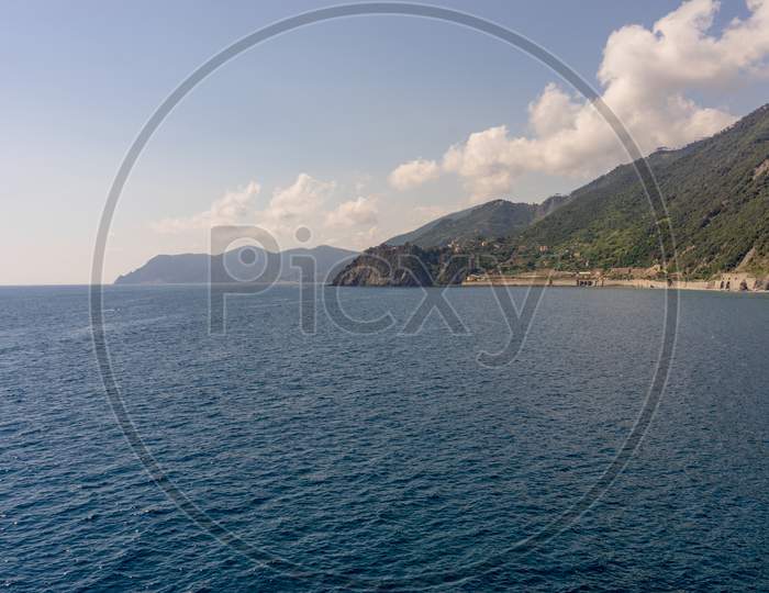 Italy, Cinque Terre, Manarola, A Large Body Of Water With A Mountain In The Background