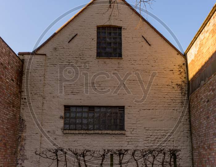 Belgium, Bruges, A Large Brick Building With A Clock On The Side Of A House