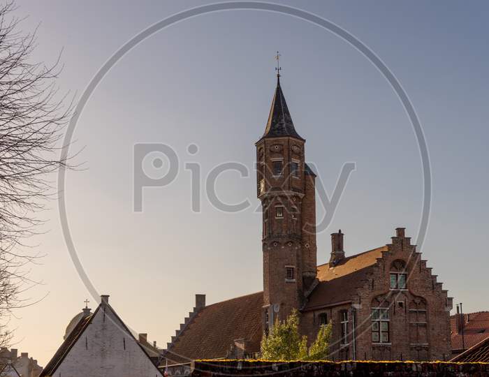Belgium, Bruges, A Small Clock Tower In Front Of A Building