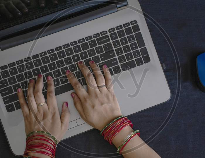 Female Wearing Bangles And Typing On Laptop.