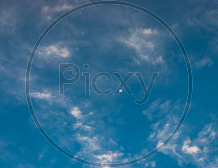 Moon With Bright Blue Sky And Clouds At Morning