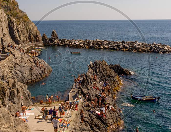 Manarola, Cinque Terre, Italy - 27 June 2018: Tourists Enjoying The Beach And Sunshine At Manarola, Cinque Terre, Italy
