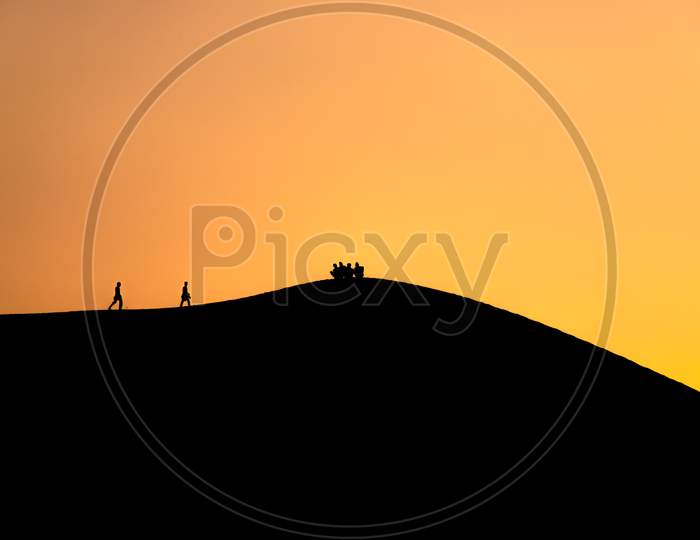 People walking on desert in silhouette