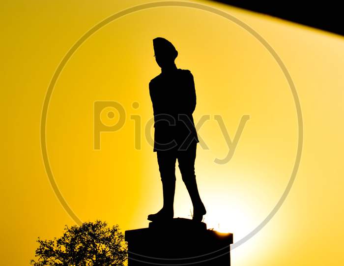 Subhash chandra bose statue in black yellow silhouette against sun