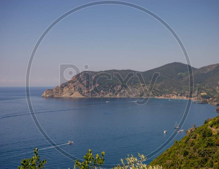 Italy, Cinque Terre, Corniglia, A Large Body Of Water With A Mountain In The Background