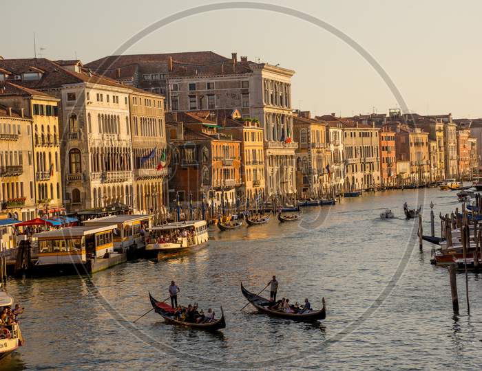Venice, Italy - 30 June 2018: Gondolier Taking Tourists On A Gondola Ride Along The Grand Canal Near Rialto Hotel In Venice, Italy