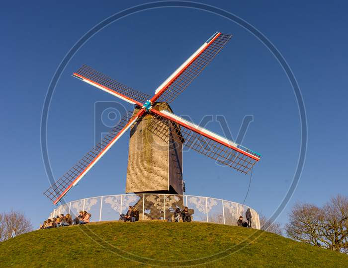 Belgium, Bruges, A Windmill On Top Of A Grass Covered Field