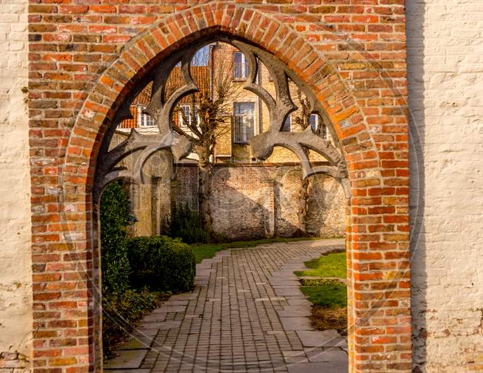 Belgium, Bruges, A Stone Building That Has A Arch On A Brick Wall