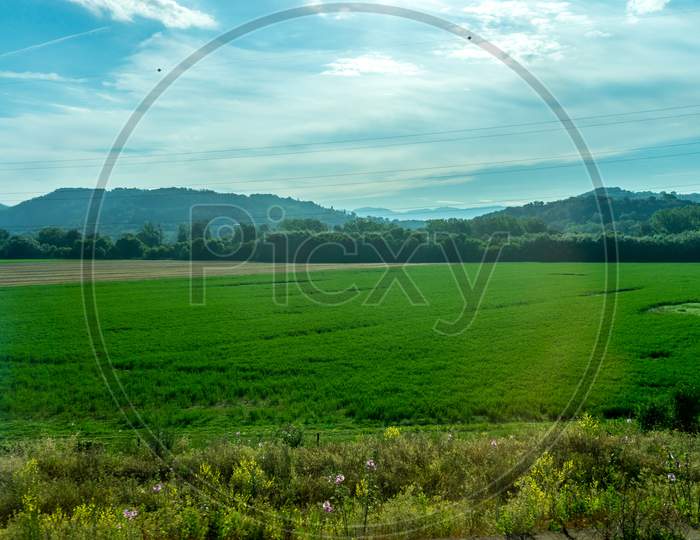 Italy, Rome To Florence Train, A Large Green Field With A Mountain In The Background