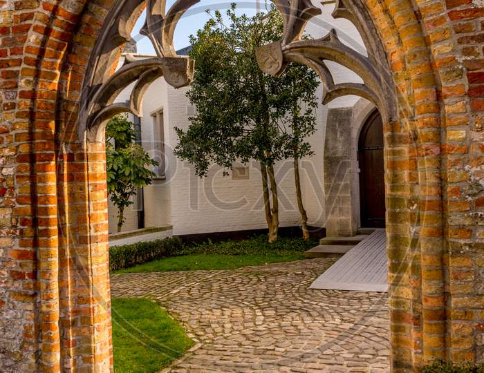 Belgium, Bruges, A Stone Building That Has A Arch On A Brick Wall