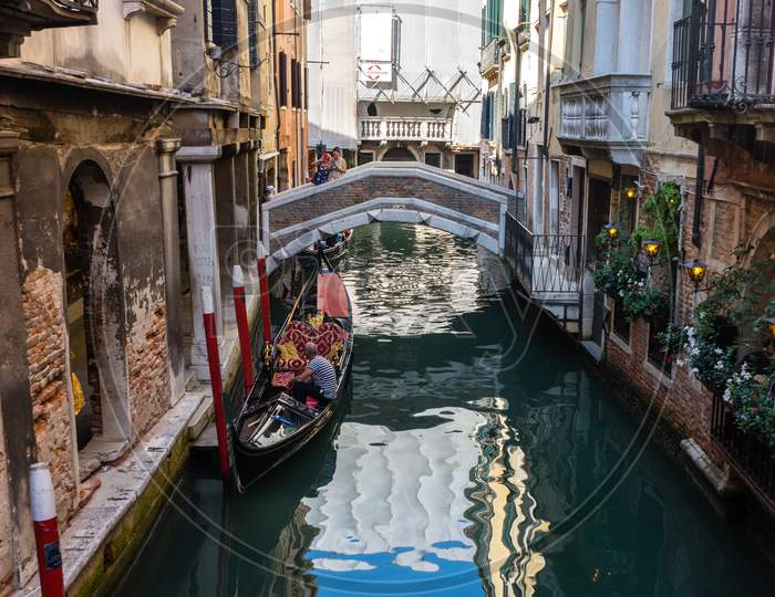 Venice, Italy - 30 June 2018: The Gondolas Parked With Gondolier Near Bridge In Venice, Italy