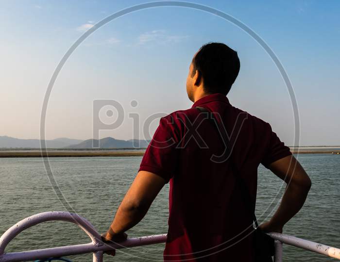 Man Posing At Ship Deck With River Horizon At Evening
