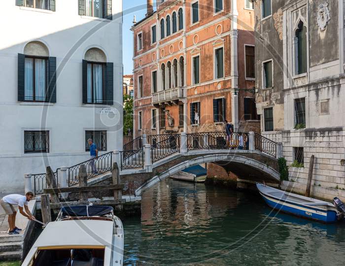 Venice, Italy - 30 June 2018: People Walking Down The Narrow Streets Of Venice Along A Canal, Italy