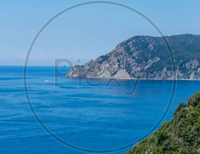 Italy, Cinque Terre, Corniglia, A Body Of Water With A Mountain In The Background