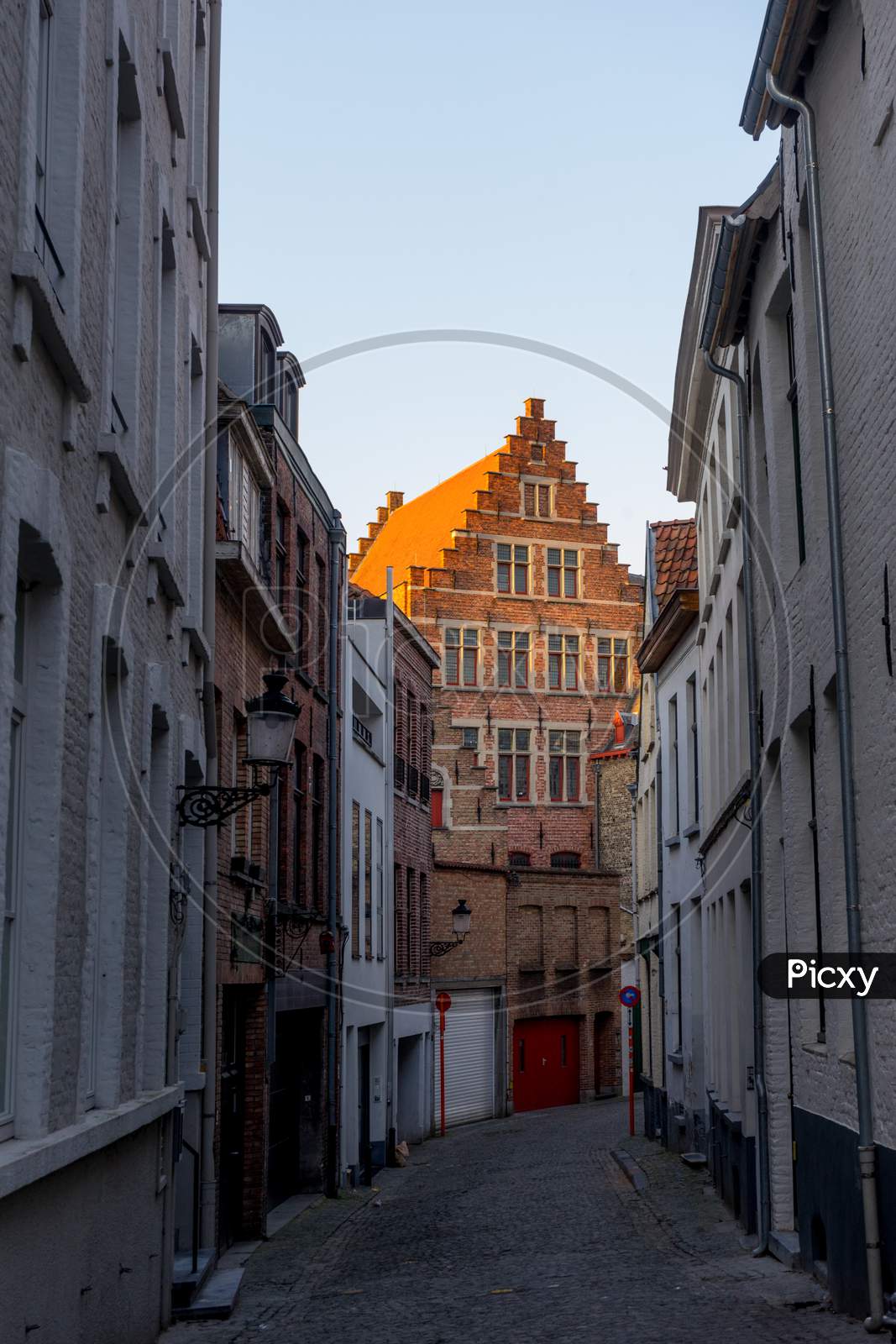 Belgium, Bruges, A Narrow City Street With Old Buildings In The Background