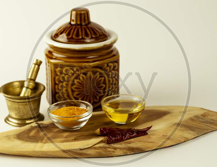 Nice arrangement of Indian spices tartaric powder, mustard oil, dry chili with hand grinder and container are kept on a wooden isolated base