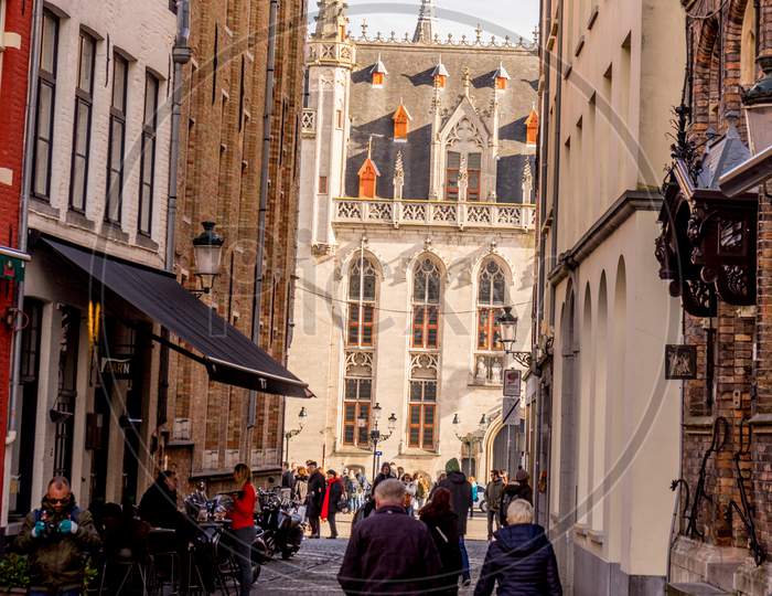 Bruges, Belgium - 17 February 2018: People Walking On A Narrow Lane Alley Near The Provincial Court At Bruges