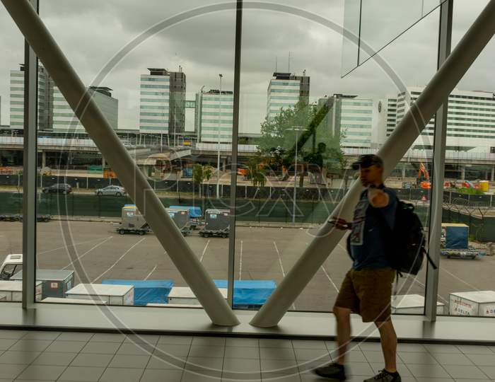 Amsterdam, Schiphol - 22 June 2018: People Walk Past The Interior Glass Windows At The Schiphol Airport