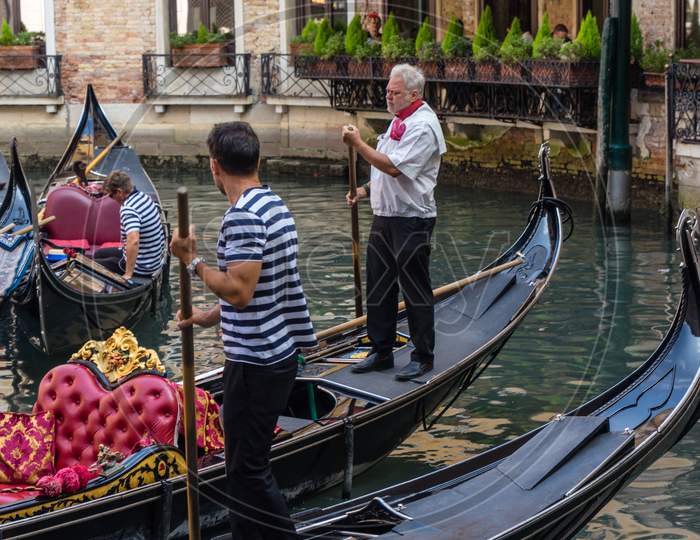 Venice, Italy - 01 July 2018: The Gondolas Parked With Gondolier Near Bridge In Venice, Italy