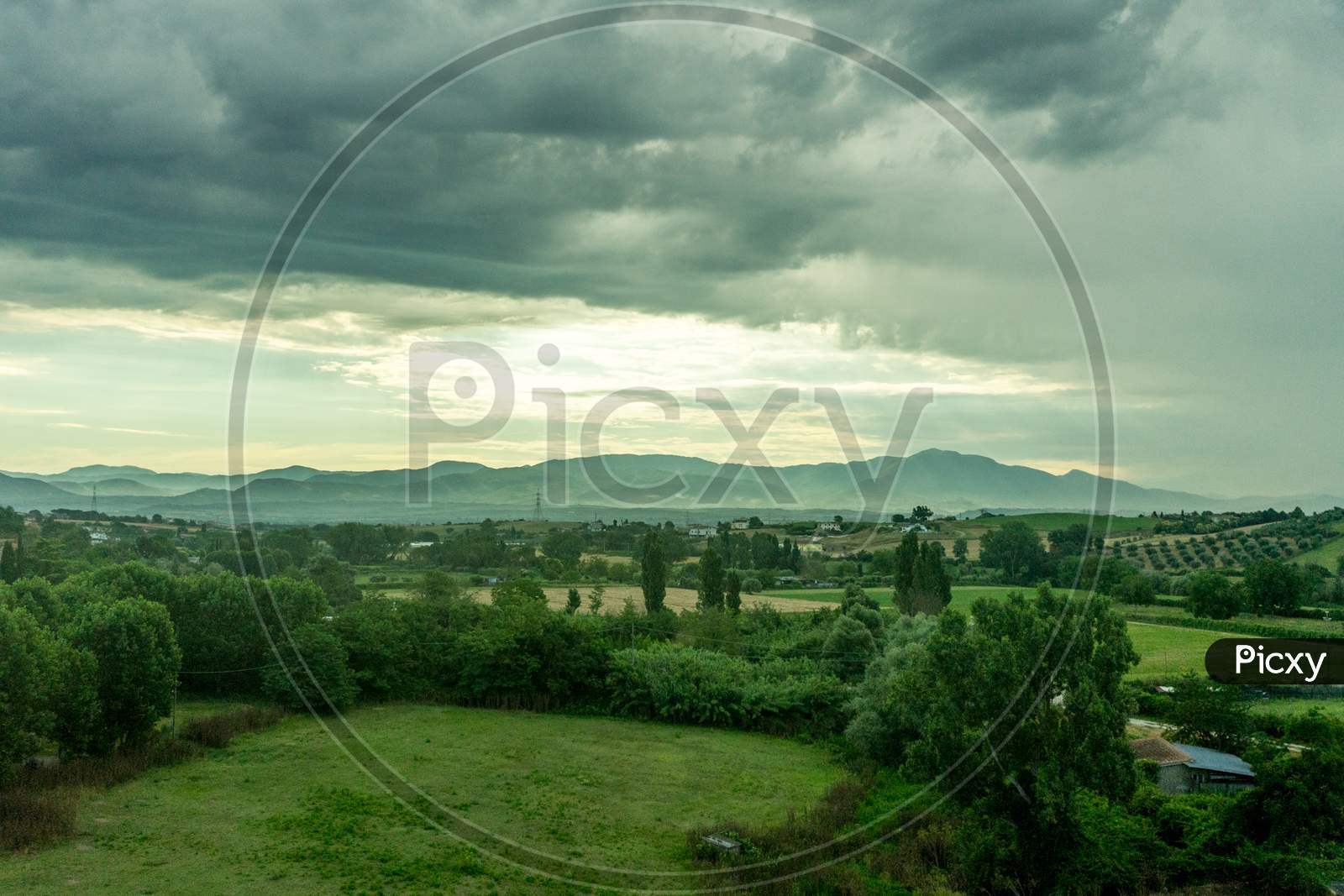Italy, Rome To Florence Train, A Large Green Field With Clouds In The Sky