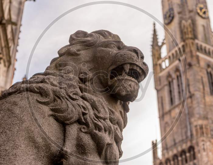 Belgium, Bruges, A Lion Statue Sitting On The Side Of A Building
