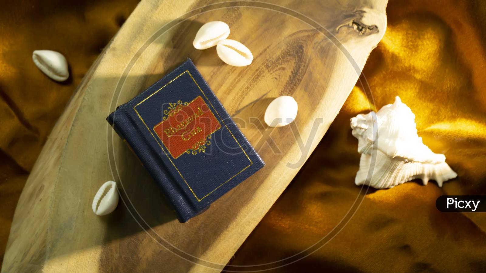 Hindu holy book and cowrie shell on a golden satin cloth with other elements of religious rituals
