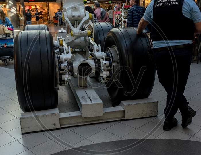 Netherlands, Amsterdam, Schiphol - 06 May, 2018: Security Standing Near Wheels Of Aeroplane At Schiphol Airport