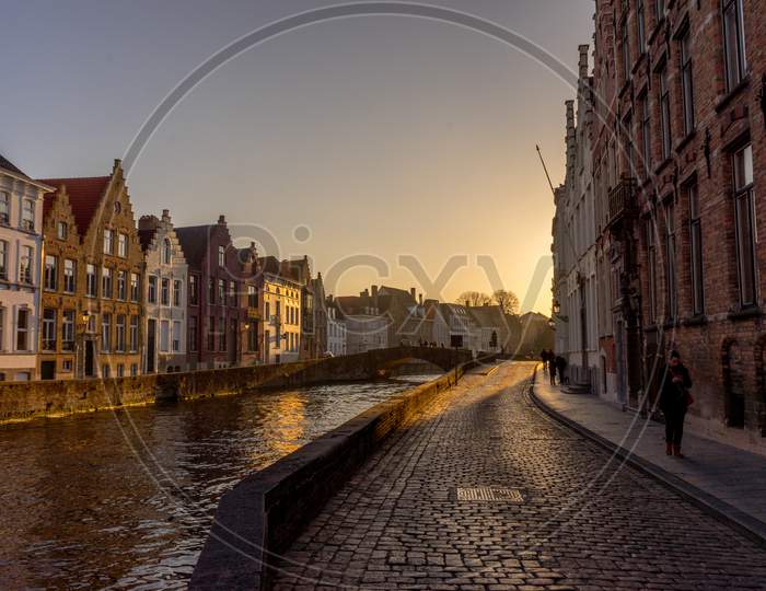 Belgium, Bruges, A Bridge Over Water With A City In The Background