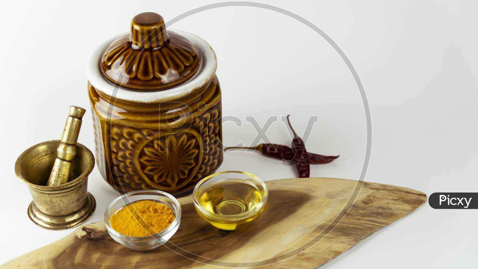 Nice arrangement of Indian spices tartaric powder, mustard oil, dry chili with hand grinder and container are kept on a wooden isolated base