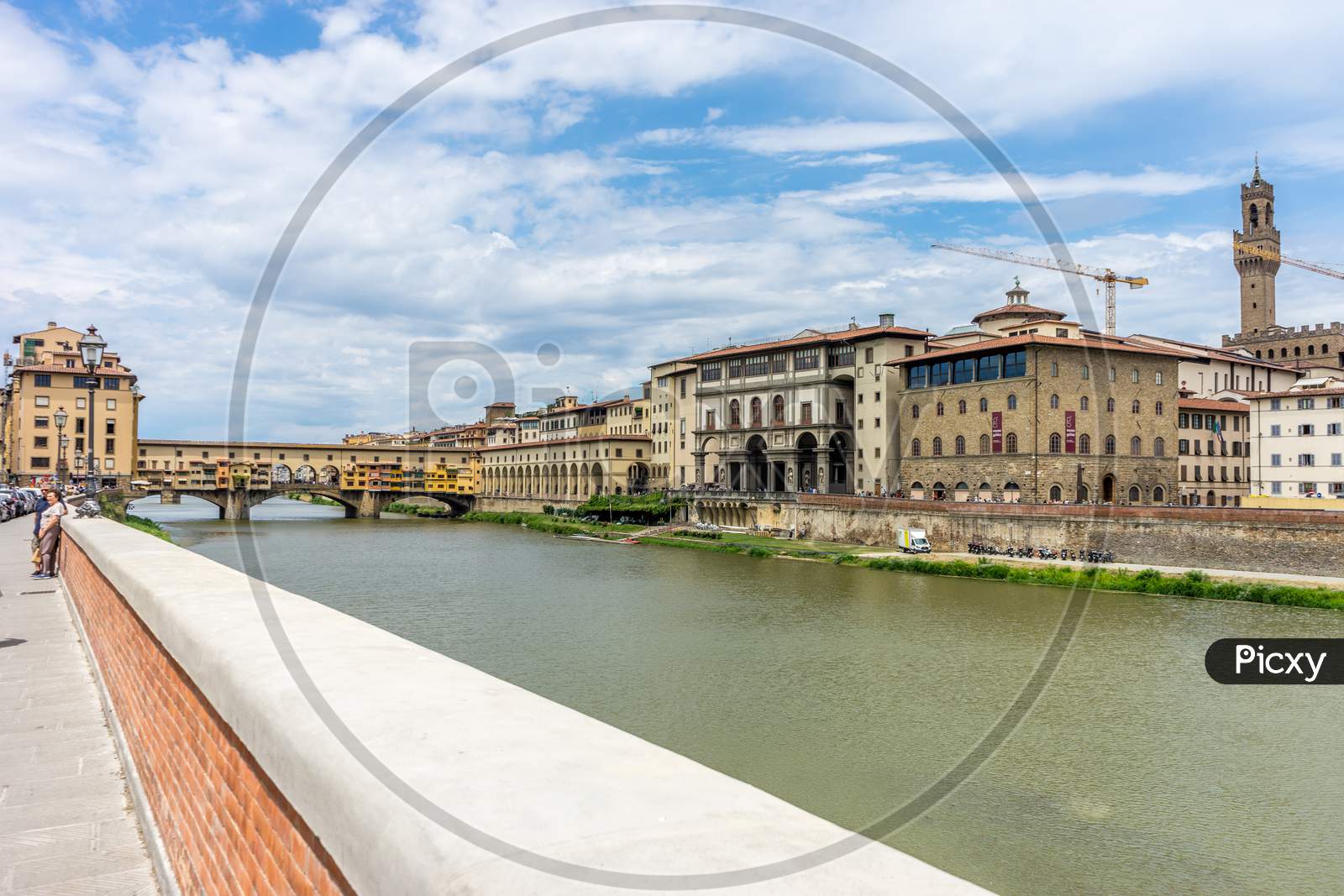 Florence, Italy - 25 June 2018: Tourists Walking Near The Ponte Vecchio Over The Arno River In Florence, Italy