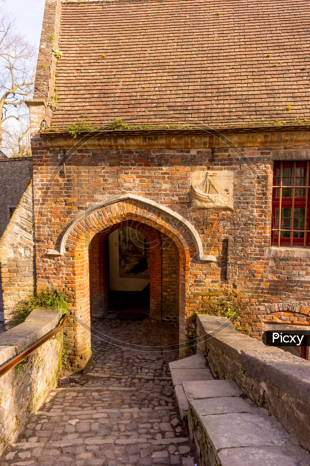 Belgium, Bruges, A Stone Building That Has A Bench In Front Of A Brick Wall