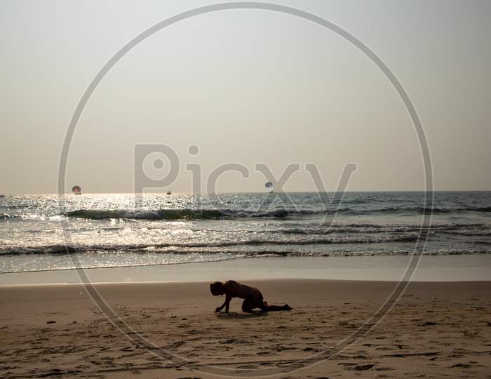 a girl is playing with sand  on the beach of goa