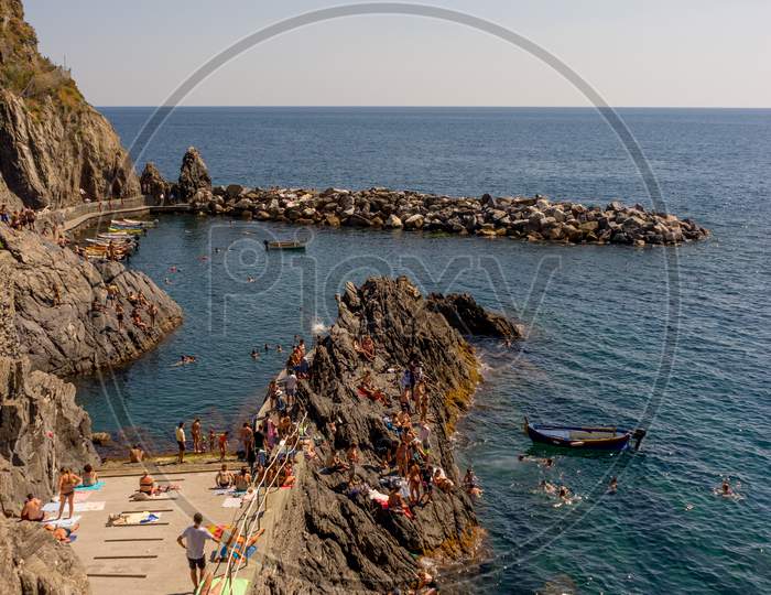 Manarola, Cinque Terre, Italy - 27 June 2018: Tourists Enjoying The Beach And Sunshine At Manarola, Cinque Terre, Italy