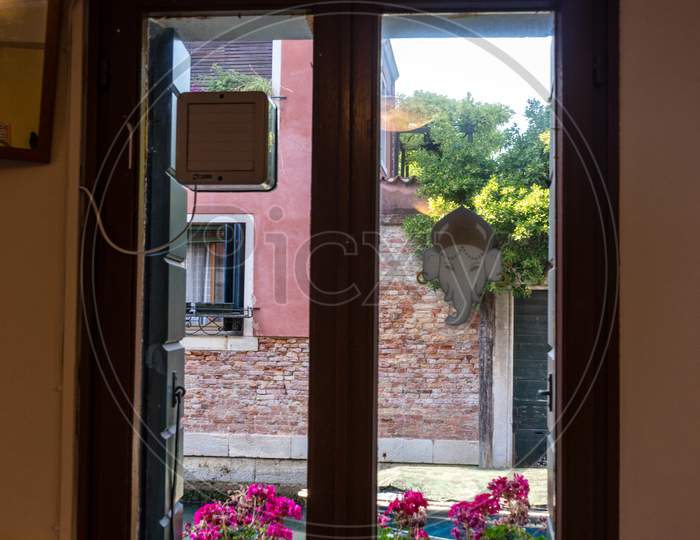 Italy, Venice, A Vase Of Flowers Sits In Front Of A Window