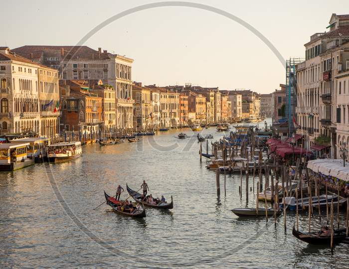Venice, Italy - 30 June 2018: Gondolier Taking Tourists On A Gondola Ride Along The Grand Canal Near Rialto Hotel In Venice, Italy