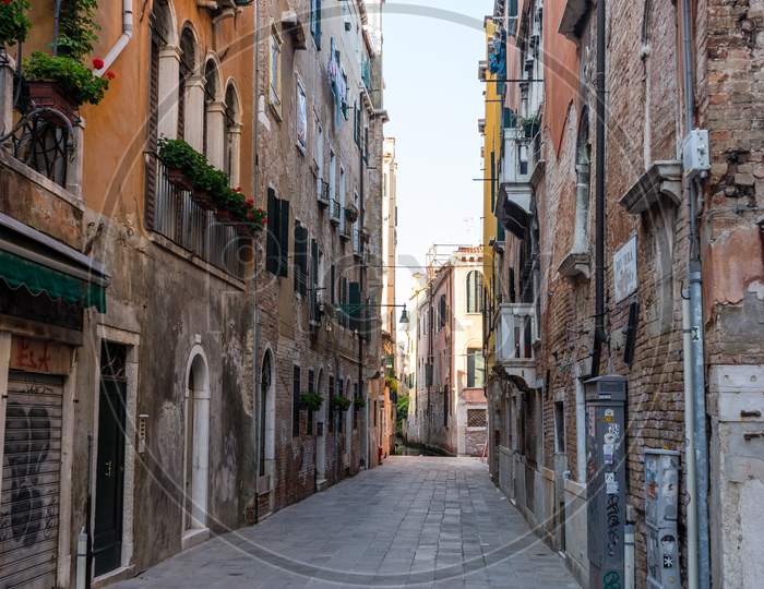 Italy, Venice, A Narrow City Street With Buildings In The Background